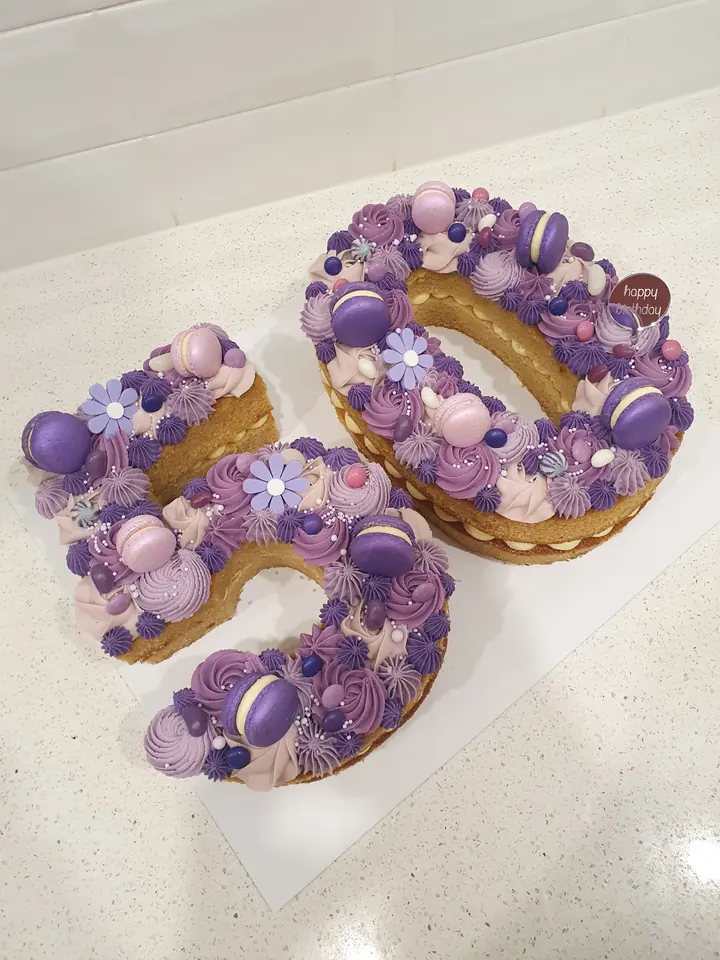 A Miss Sprinkles number cake shaped as 50, piped in lilac and purple